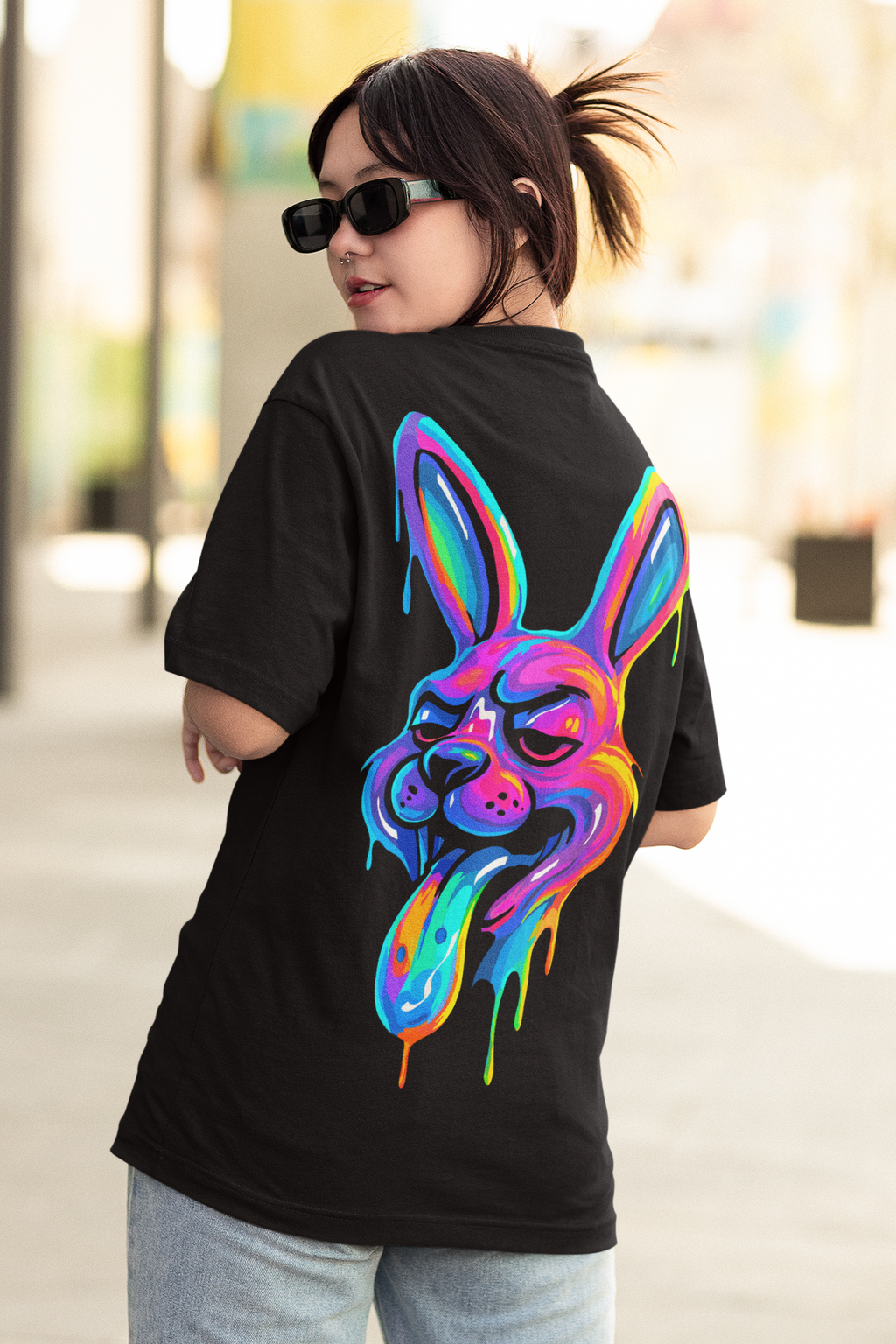 Model wearing JACKRABBIT psychedelic rabbit oversized t-shirt by LMNO streetwear, wearing sunglasses and looking back