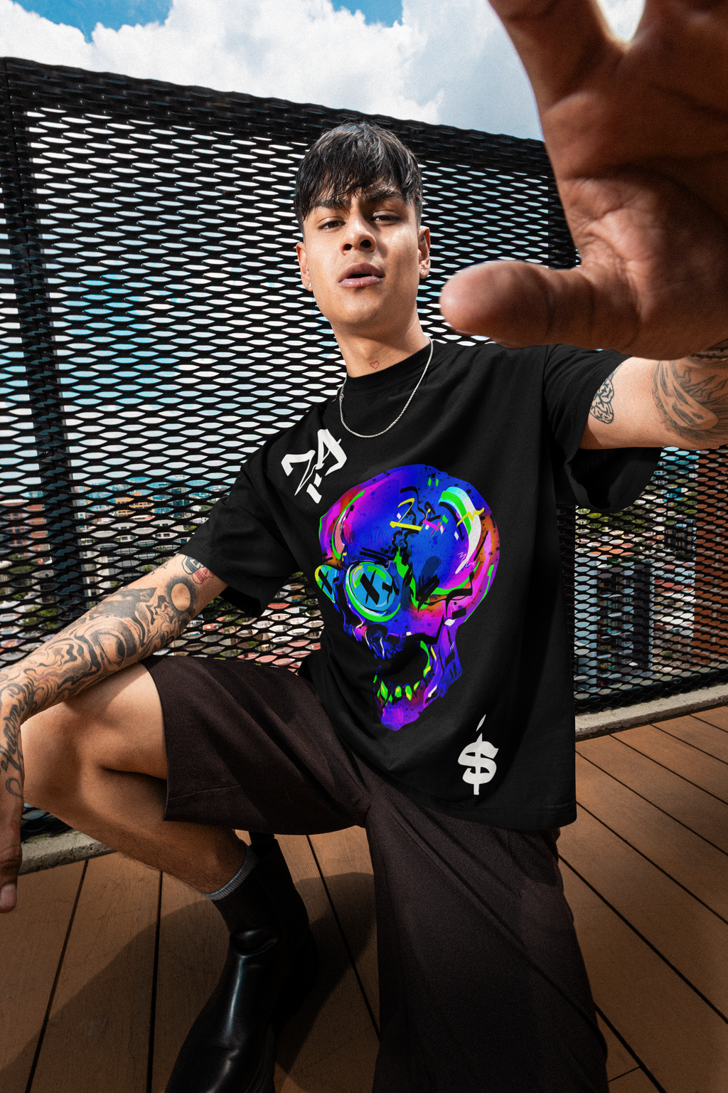Model wearing OVERDRIVE neon skull oversized t-shirt by LMNO streetwear, kneeling and holding a camera